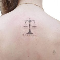 the back of a woman's neck with a scale tattoo on her left shoulder