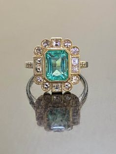 DeKara Designs Classic Handmade Art Deco Oval Emerald and Diamond Ring. Metal- 14K Yellow Gold, .583 Stones- GIA Certified Elongated Octagonal Colombian Emerald 1.99 Carats, 14 Single Cut Round Diamonds G-H Color VS2-SI1 Clarity 0.52 Carats, 6 Square Baguette Diamonds G-H Color VS2-SI1 Clarity 0.50 Carats. GIA Report Number 2225040369 An amazing entirely handmade GIA Certified Elongated Colombian Emerald and Antique Diamond Engagement Ring Created in 14K Yellow Gold. There is a beautiful blue gr Art Deco Green Ring, Gia Certified, Art Deco Green Ring Gia Certified, Gia Certified Rectangular Gold Diamond Ring, Gia Certified Oval Emerald Ring In Art Deco Style, Gia Certified Rectangular Emerald Ring For Anniversary, Gold Emerald Ring With Radiant Cut, Gold Radiant Cut Emerald Rings, Gold Emerald Cut Gemstone Halo Ring, Heirloom Cluster Ring With Emerald Cut Gemstone