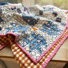 a quilted table runner sitting on top of a wooden table next to a window