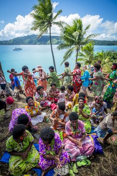 a group of people sitting on top of a hill next to the ocean