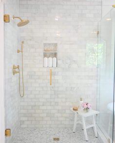 a walk in shower sitting next to a white table with flowers and candles on it