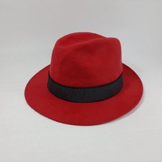 Only size:62cm. The hat's brim is asymmetrical and it also includes an additional rubber band for added style. The whole look can be seen in the attached pictures. This hat is a part of our company's archival collection. Introducing the iconic fedora hat, expertly crafted using traditional sewing techniques to ensure a flawless finish. This timeless design features a built-in lining for extra comfort and warmth, while its sleek black band and sturdy construction make it suitable for all weather conditions, making it a reliable choice for any occasion. Made from premium wool fabric, this fedora exudes sophistication with a touch of vintage charm.  WPZ-BSS-W10-62-v1259 Red Fitted Fedora For Party, Red Fitted Felt Hat For Formal Occasions, Formal Red Fitted Felt Hat, Classic Red Fitted Top Hat, Classic Red Fedora Felt Hat, Red Fedora With Curved Brim For Formal Occasions, Red Fitted Fedora With Curved Brim, Classic Red Fedora With Curved Brim, Fitted Red Fedora With Curved Brim