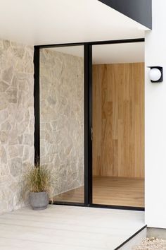 an open door to a room with stone walls and wooden doors on either side, next to a potted plant