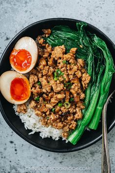 a bowl filled with rice and meat next to an boiled egg on top of it