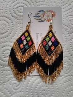 These Earrings are made by hand by me. There are 9 triangles in different colors bordered in Black and Gold. They have Gold and Iris Fringe approximately 1 1/4 inches long. They are in total 3 inches in length. They are made with Miyuki Delica size 11 seed beads. Made to Order means you purchase then I will make it within 3 days.I can make them bordered in other colors also.  Please take a close look at my work. Thank You So Very Much for your Interest Bohemian Triangle Adjustable Earrings, Bohemian Adjustable Triangle Earrings, Adjustable Bohemian Triangle Earrings, Handmade Triangle Bohemian Jewelry, Handmade Bohemian Triangle Jewelry, Bohemian Triangle Earrings With Ear Wire, Handmade Triangle Earrings For Festival, Unique Handmade Triangle Earrings, Multicolor Beaded Earrings With Latkans As Gift