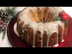 a bundt cake with icing on a red plate next to pine cones and christmas decorations