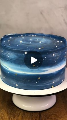 a blue and white cake with stars on it sitting on top of a wooden table