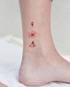 a woman's foot with three pink flowers on her left ankle and one flower on the right side