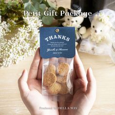 a person holding a package of cookies in front of a table with flowers and teddy bears