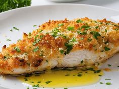 a white plate topped with fish covered in parmesan cheese and garnish