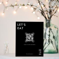 there is a card that says let's eat on it next to a vase with flowers