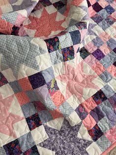 a pink and blue quilt on top of a bed