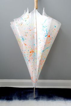 an upside down umbrella with paint splattered on it hanging from a hook against a wall