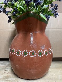 a brown vase with blue flowers in it