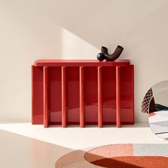 a red cabinet sitting on top of a white floor next to a mirror and rug