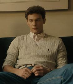 a man sitting on top of a couch wearing a sweater