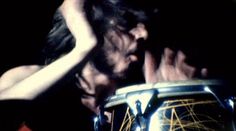 a man with long hair holding a drum in front of his face and looking at it