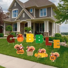 a house with thanksgiving decorations on the lawn and in front of it, there is a sign that says gobble