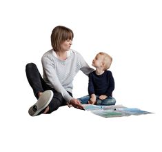 a woman sitting on the floor with a baby next to her, both looking at each other