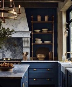 a kitchen with blue cabinets and marble counter tops, gold accents on the shelves and brass fixtures