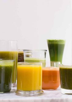 there are many different types of juices on the table together, including orange, green and yellow