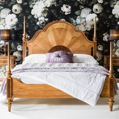 a wooden bed sitting in front of a floral wallpaper