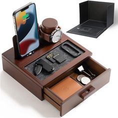 an iphone is sitting on top of a wooden box with other items in it, including a watch and wallet