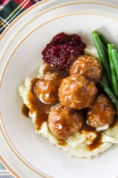 meatballs, mashed potatoes and green beans on a plate with cranberry sauce