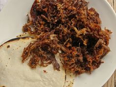 two tortillas on a white plate with shredded meat