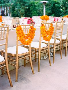 the chairs are decorated with orange flowers and white linens for an outdoor wedding reception