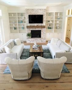 a living room filled with white furniture and a flat screen tv mounted above a fireplace