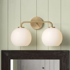 two lights on the wall above a mirror in a room with green walls and wood paneling