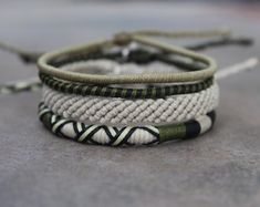 three different bracelets with green and white cords on concrete surface, close up view