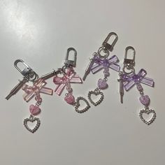 four charms with hearts and bows on them sitting next to each other in the shape of letters