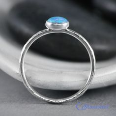 This Sterling Silver Blue Opal Ring features an 8 mm x 6 mm oval lab grown Blue Opal cabochon that has been securely set in a highly polished fine silver bezel. The band is made of a sturdy round Sterling Silver wire that has a hammered texture around the entire band. These beautiful rings make unique promise rings, lovely stacking rings, great birthstone rings, or just a wonderful love tokens for yourself or your special someone. This man-made Blue Opal is created from very uniform nanoparticle Minimalist Oval Blue Ring, Blue Oval Stackable Rings For Anniversary, Oval Blue Sterling Silver Stackable Rings, Blue Oval Stackable Promise Rings, Oval Opal Stackable Rings, Blue Oval Stackable Rings As Gift, Blue Oval Stackable Rings For Gift, Stackable Oval Opal Rings, Adjustable Stackable Oval Opal Ring