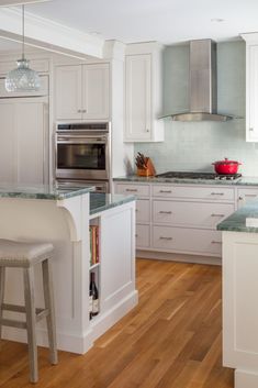 a kitchen with white cabinets and wooden floors