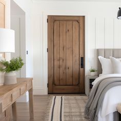 a bed sitting next to a wooden door on top of a white wall in a bedroom