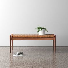 a wooden bench with a potted plant on top of it next to a pair of slippers