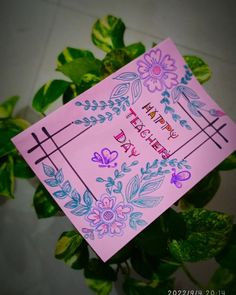 a pink card that says happy birthday with flowers and crosses on the front, surrounded by green leaves