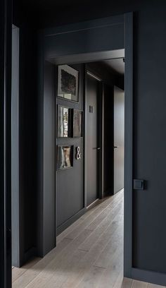 an open door leading into a room with wood floors and black walls, along with pictures on the wall