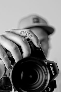 black and white photograph of a person holding a camera with the word smile written on it