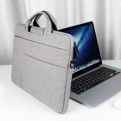 an open laptop computer sitting on top of a white table next to a gray bag