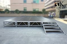 an outdoor stage set up in the middle of a parking lot with steps leading to it