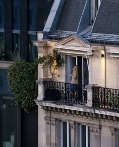 a woman standing on the balcony of an apartment building