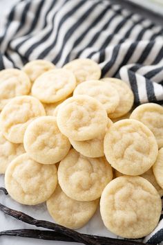 a bunch of cookies sitting on top of a white and black cloth next to vanilla sticks