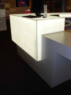 a white desk with a phone on it in front of a television screen and bookshelves