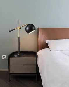 a bedroom with a bed, nightstand and lamp on the night stand next to it