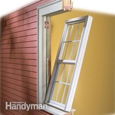 an open window on the side of a red house with yellow walls and sidings