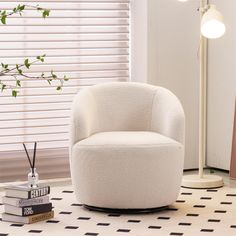 a white chair sitting on top of a floor next to a lamp and book shelf