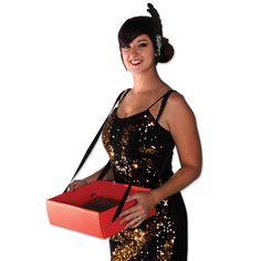 a woman in a black and gold dress holding a red box